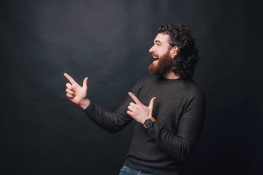 Kıvırcık saçlı, esmer ve gülümseyen yakışıklı sakallı adam.