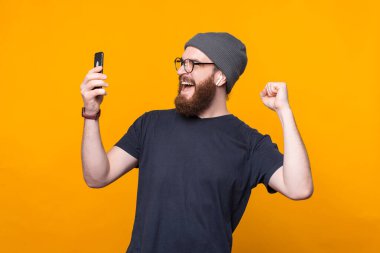 Afallamış sakallı hippi adamın fotoğrafı. Akıllı telefona bakıyor ve kutluyor.