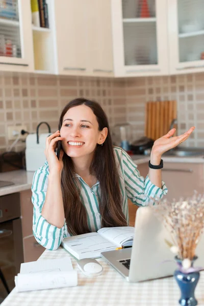 Happy pracownik kobieta rozmawia przez telefon podczas siedzenia w kuchni — Zdjęcie stockowe