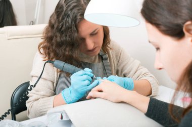 Güzellik salonunda manikür yapan bir kadın.