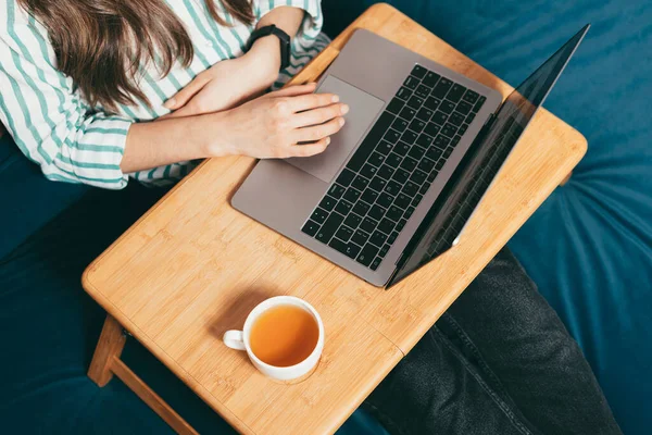 Kvinna som arbetar hemifrån på bärbar dator medan du sitter på soffa ovanifrån — Stockfoto