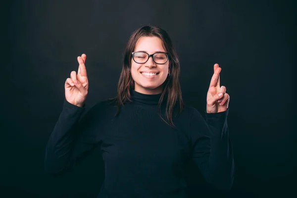 Esperando que la chica sonriente cruce sus dedos con los ojos cerrados. — Foto de Stock