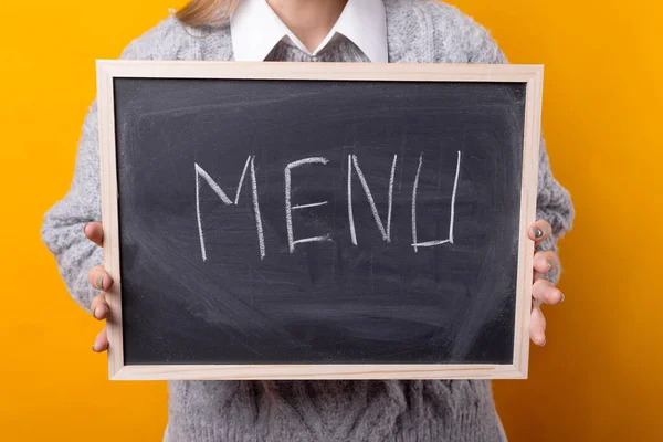 Girl holding a small blackboard with menu word written on it. — Stock Photo, Image