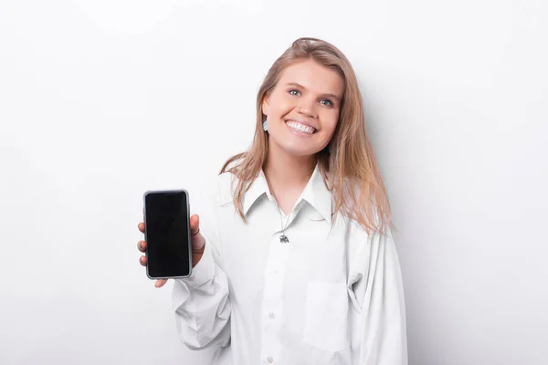 Photo of smiling happy young woman over white background showing smartphone — Stock Fotó
