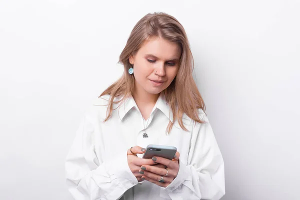 Photo of young woman in white shirt using smartphone over white background — Stock Photo, Image