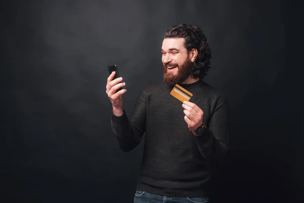 Cheerful young man using his credit card for online web banking — Stockfoto