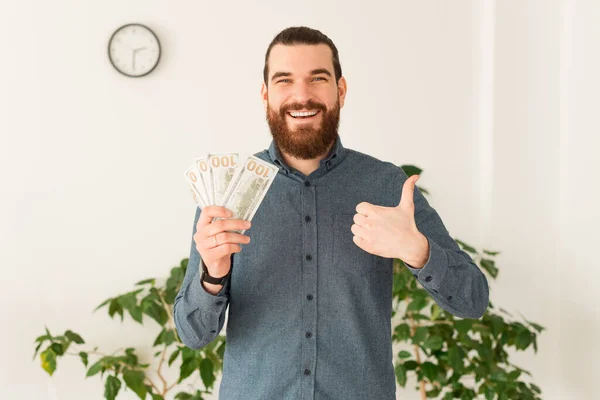 Happy office worker man holding money in hand and showing thumb up — Stock Photo, Image