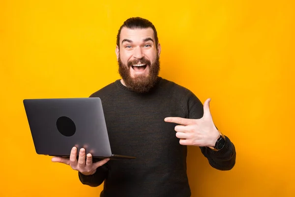 Photo de l'homme barbu étonné pointant vers un ordinateur portable — Photo