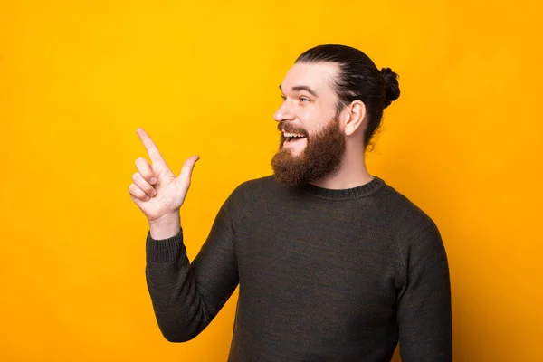Side view portrait of joyful bearded hipster man pointing in the corner — Stock Fotó