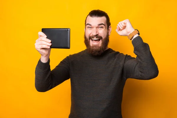 Homme barbu joyeux tenant tablette et célébrant la victoire — Photo