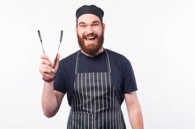 Mutlu aşçının et pişirmek için çatal bıçak tutarken fotoğrafı.