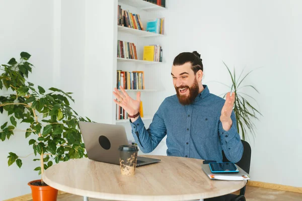 Photo of amazed man looking at laptop in office and gesturing