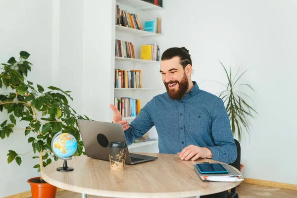 Foto de hombre barbudo guapo feliz charlando en línea en la oficina —  Fotos de Stock