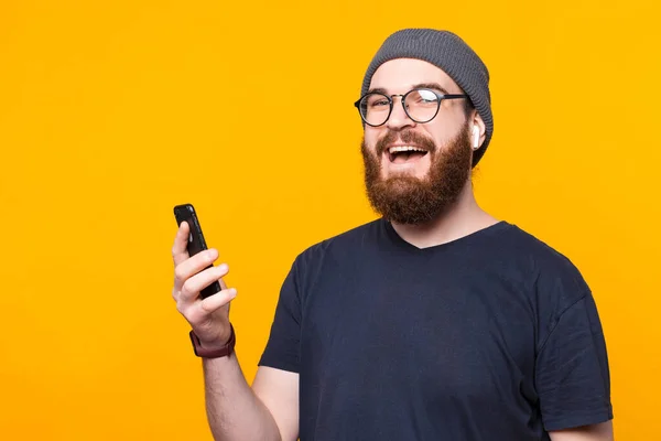 Photo d'un hipster barbu utilisant un smartphone et portant des écouteurs — Photo