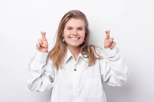 Foto de una joven sonriente cruzando los dedos sobre fondo blanco — Foto de Stock