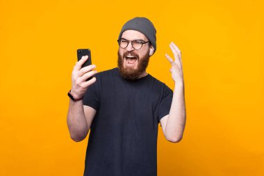 Sakallı hippi adamın akıllı telefona kızgın bakışları.