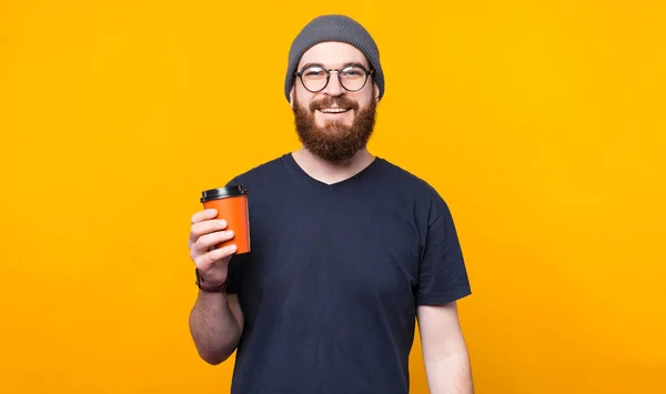 Бородатий хіпстер тримає чашку кави, щоб піти і посміхатися — стокове фото