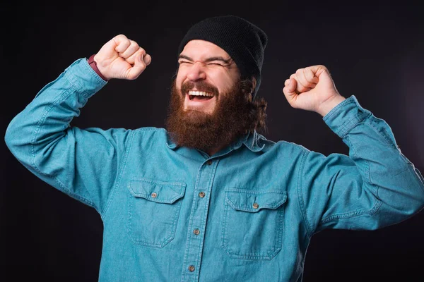 Portrét vousatý hipster muž slaví vítězství nad černým pozadím — Stock fotografie