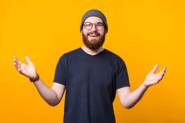 Neşeli genç bir adam kameraya bakıyor ellerini kaldırıyor ve sarılmak istediğini gösteriyor.