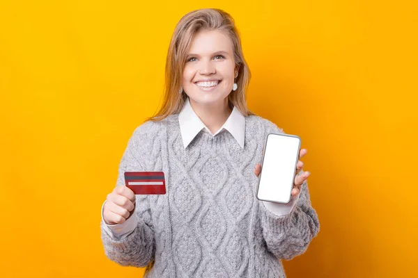 Uma mulher alegre está comprando on-line de seu celular e cartão de crédito — Fotografia de Stock
