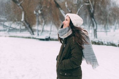 Genç güzel bayan kışın bir ormanda gülümsüyor ve uzaklara bakıyor.