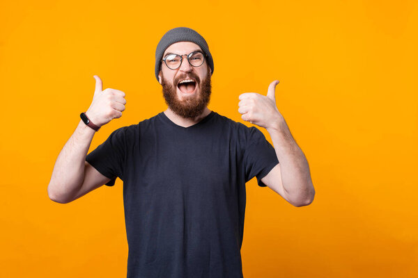 An very excited man with beard and glasses is showing thumbs up at the camera