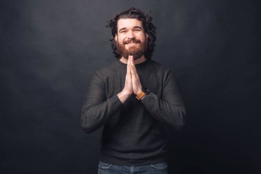 Siyah bir duvarın yakınındaki kameraya bakan bir adamın resmi.