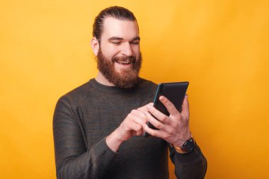 Neşeli sakallı bir adam tabletinde mutlu biriyle konuşuyor.