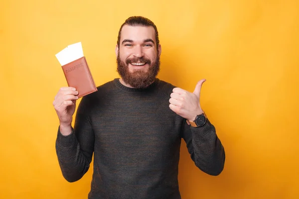 Ein Foto von einem Mann, der lächelnd einen Reisepass mit zwei Eintrittskarten in der Hand hält — Stockfoto