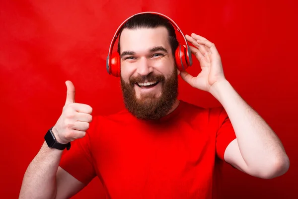 Ein Bild, auf dem ein Mann mit Bart zeigt, dass ihm die Musik gefällt, die er über Kopfhörer hört — Stockfoto