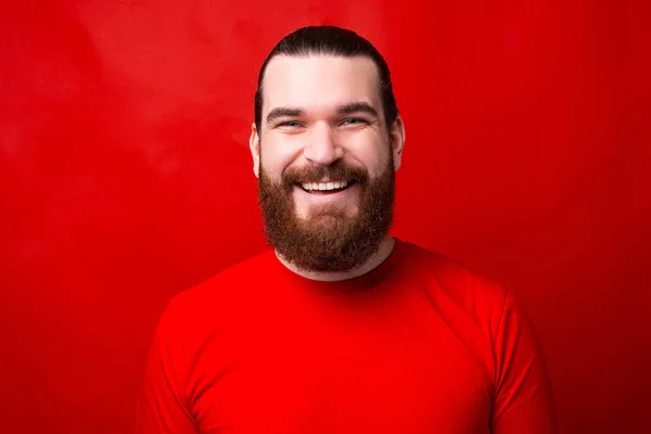 Красивая фотография человека, смотрящего и улыбающегося в камеру у красной стены — стоковое фото