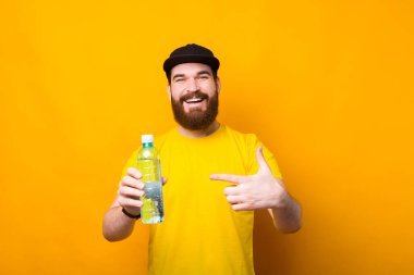 Neşeli genç bir adamın temiz su şişesini göstererek her gün su içtiği fotoğraf.