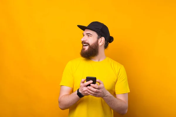 Porträt eines gutaussehenden jungen Mannes mit Bart, der sein Smartphone in der Hand hält und den Copyspace betrachtet — Stockfoto
