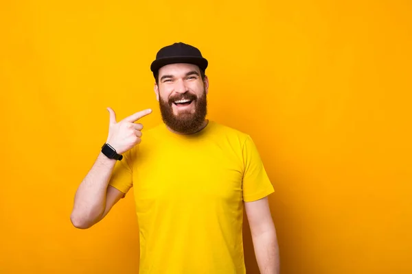 Foto von gutaussehenden bärtigen Hipster-Mann zeigt auf sein Lächeln über gelbem Hintergrund — Stockfoto