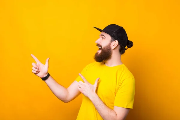 Foto eines erstaunten Mannes mit Bart, der ein gelbes T-Shirt trägt und in Richtung Copyspace zeigt — Stockfoto