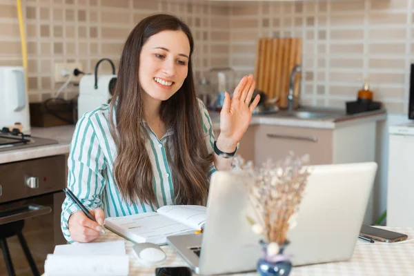 Фото улыбающейся женщины, работающей из дома на ноутбуке онлайн — стоковое фото