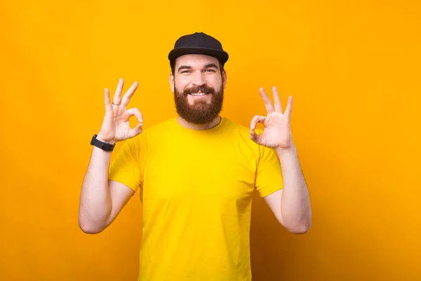 Foto eines fröhlichen jungen Mannes im gelben Hemd, der OK-Geste zeigt und in die Kamera lächelt — Stockfoto