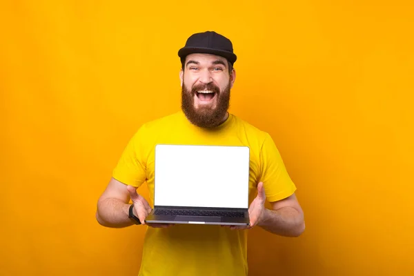 Retrato del joven barbudo gritando asombrado mostrando la pantalla vacía del ordenador portátil — Foto de Stock