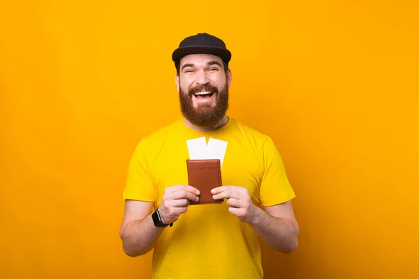 Porträt eines erstaunten lächelnden Mannes mit Bart, der Pass und Flugtickets in der Hand hält — Stockfoto