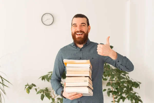 Porträt eines lächelnden Büroangestellten, der viele Bücher hält und den Daumen nach oben zeigt — Stockfoto