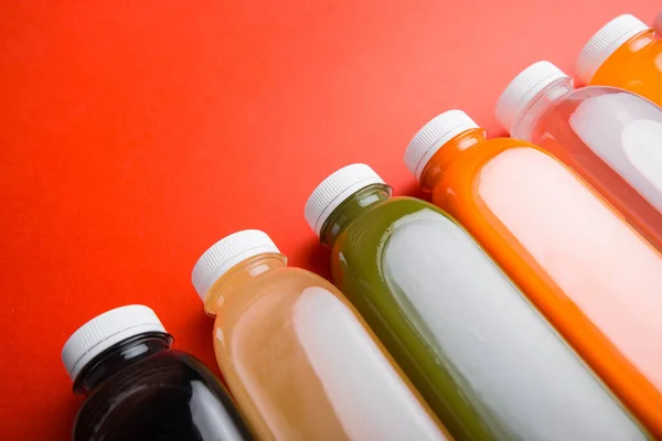 Foto de muchas botellas de jugo fresco de desintoxicación sobre fondo rojo — Foto de Stock