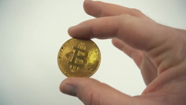 Close up video of man holding golden bitcoin over white background — Stock Video