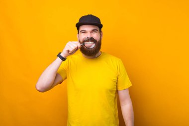 Neşeli sakallı hippi, dişlerini büyüteçle gösteriyor.