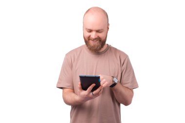 Beyaz arka planda tablet kullanan neşeli, genç sakallı adam.