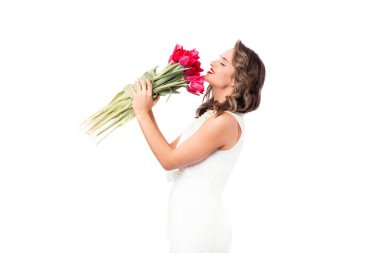 Beyaz giyinmiş, pembe laleler kokan çekici bir kadının fotoğrafı.