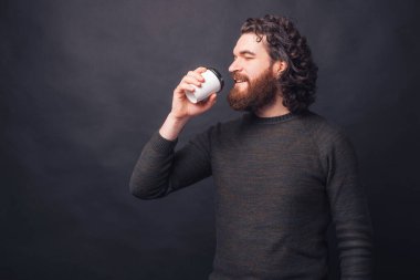 Yakışıklı, sakallı, genç bir adam bir fincan kahve içiyor..