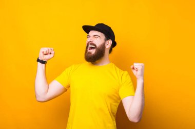 Şaşırmış bir adamın portresi sarı arka plandaki zaferi kutluyor..