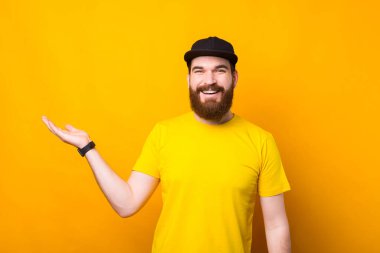 Palmiye boşluğunda bir ürünü tutan mutlu sakallı adamın fotoğrafı..