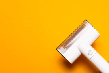 Sarı zemin üzerinde taşınabilir elektrik süpürgesinin üst görünümü.