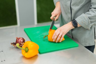 Şef 'in kesme tahtasında sarı biber keserken yakın çekilen fotoğrafı..